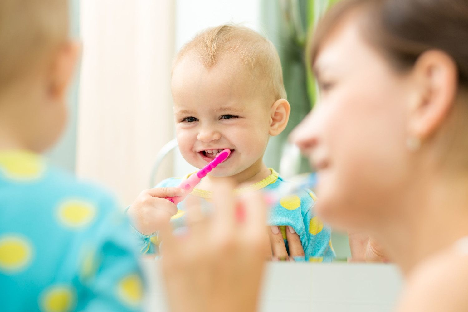 Mutter übt mit Kind das Zähneputzen 